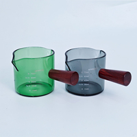 Vaso medidor de vidrio verde de 75 ml / 2.2 oz con un solo mango de madera para extractos de sabor, alimentos, concentrados de café y bebidas espirituosas.