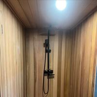 Sauna extérieur moderne en bois massif avec douche intégrée et poêle à bois
