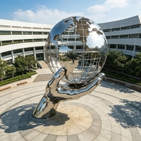 Grande sculpture de globe terrestre creux en acier inoxydable poli miroir, en forme de main tenant un globe, pour l'aménagement paysager des places universitaires