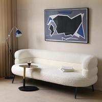 Chaise longue incurvée blanche en bouclette, fauteuil avec rembourrage moelleux, accoudoirs à niveaux, pieds en bois, design moderne pour salon et hôtel