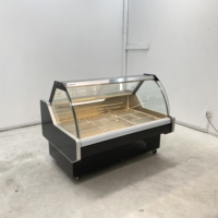 Vitrine réfrigérée moderne en verre incurvé pour la présentation de fromages artisanaux dans les sections de charcuterie des magasins spécialisés en produits alimentaires.
