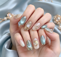 Ongles courts ovales minimalistes style Instagram, motif œil de chat vert raisin, fleur dorée 3D, paillettes, strass et fragments de perles