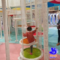 Structure de grimpette intérieure multi-niveaux en filet blanc avec poteaux rembourrés et plateformes colorées – Équipement commercial pour centre de jeux pour enfants