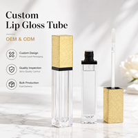 Tube de gloss cosmétique vide transparent carré avec bouchon doré et bordure noire, personnalisable avec logo, avec applicateur à baguette