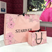 Sac en papier personnalisé imprimé rose clair avec laminage brillant, poignées en corde noire et doublure intérieure rouge pour l'emballage de vêtements féminins