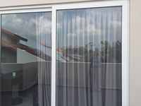 Fenêtre coulissante verticale en PVC-U au design moderne pour salon, idéale pour rideaux suspendus et usage hôtelier