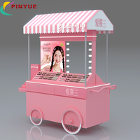 Chariot de présentation mobile haut de gamme rose personnalisé pour cosmétiques et parfums, avec auvent et roues, idéal pour les événements en centre commercial