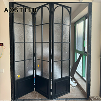 Porte pliante AOSTTER en aluminium finition noire minimaliste avec panneau de sécurité haute transparence et seuil encastré pour villa contemporaine