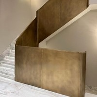 Rampe d'escalier moderne de luxe en acier courbé avec finition bronze antique et texture marbre en tons chauds pour villa intérieure