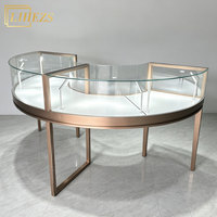 Vitrine de présentation de bijoux en acier inoxydable doré rose incurvé, élégante et luxueuse, avec verre pleine vue et éclairage LED, pour boutique de bijoux.