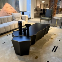 Table basse moderne noire mate avec bord ondulé et finition dorée, forme irrégulière festonnée, base solide pour salon