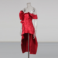 Gaun pesta wanita tanpa tali, model high-low dengan ruffle, warna merah merah tua, asimetris, dengan detail cascading di sisi, mini di bagian depan, dan ekor panjang.