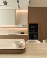 Ensemble d'armoires de cuisine minimalistes haut de gamme, meubles en bois chaud sans poignées, crédence en pierre de travertin pour projets de rénovation