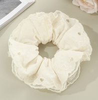 Bandeau pour cheveux avec dentelle ajourée en forme de cœur et cordon à franges pour une coiffure chignon douce et charmante.