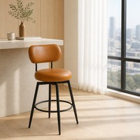 Chaise de bar pivotante en cuir caramel avec dossier incurvé, coussin rond rembourré, pieds noirs et anneau repose-pieds, idéale pour café