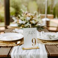 Numéros de table de mariage en acrylique blancs avec numéros sérigraphiés or et supports de présentation