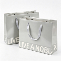 Sac cadeau en papier blanc minimaliste OEM/ODM avec poignées en ruban et typographie noire audacieuse pour la promotion d'emballages de marques de luxe modernes