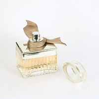 Perfume Femenino en Envase Rectangular de Vidrio con Franjas Plateadas, Lazo de Cinta Marrón, Tapa Dorada y Caja Dorada. Aroma Atemporal para Aniversario.