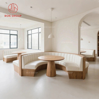 Ensemble de banquette moderne et confortable avec structure métallique incurvée et revêtement en cuir blanc, table ronde en bois pour restaurant ou café