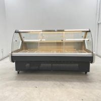 Vitrine réfrigérée moderne en verre incurvé pour la présentation de fromages artisanaux dans les sections de charcuterie des magasins spécialisés en produits alimentaires.