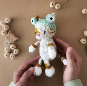 かぎ針編みの猫の子供のおもちゃカエルの帽子をかぶったキュートで愛らしいキティの手作り猫茶色のアミグルミベアのおもちゃ