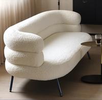 Chaise longue incurvée blanche en bouclette, fauteuil avec rembourrage moelleux, accoudoirs à niveaux, pieds en bois, design moderne pour salon et hôtel
