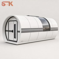 Capsule habitable avec chambre, salon, salle de bain, fenêtre incurvée en verre, lucarne, coque blanche, cadre foncé, maison capsule préfabriquée