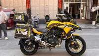 Moto de tourisme d'aventure à deux cylindres refroidie par eau de 502 cm3, blanche et noire, avec bagages et barres de protection entièrement en aluminium
