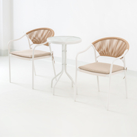 Ensemble bistrot 3 pièces aspect rotin, table ronde avec plateau en verre et 2 chaises à accoudoirs tressés avec coussin, cadre blanc, ensemble de jardin extérieur
