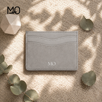 Porte-cartes en cuir gris clair, portefeuille fin avec panneau avant aspect daim, fentes incurvées pour cartes et logo métallique, idéal pour les commandes de marques de détail