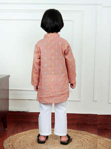 Lindo niño pequeño con kurta color melocotón con estampado colorido y pijama blanco, sonriendo en el interior con un atuendo festivo tradicional. - Product Image 4