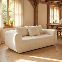 Canapé 3 places en tissu bouclé crème, capitonné, à profil bas et accoudoirs arrondis, pour maison rustique avec poutres en bois