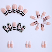 Uñas postizas de moda estilo Y2K con diseño de estrella y remolino, base nude, forma ataúd larga, arte de uñas gráfico en blanco y negro con pequeños detalles de diamantes de imitación.