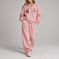 Ensemble deux pièces sport streetwear pour femme : sweat à capuche oversize zippé à épaules tombantes et pantalon de survêtement large brodé avec patchs rétro