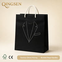 Sacs shopping personnalisés OEM en papier noir mat avec logo imprimé, poignées en corde tressée et œillets métalliques, réutilisables pour les boutiques de vêtements pour hommes