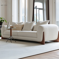 Canapé d'intérieur moderne avec accoudoirs arrondis rembourrés en blanc, pieds décoratifs en bois et coussins décoratifs pour salon