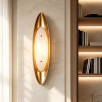 Applique murale moderne de luxe en albâtre avec cadre en métal doré brossé et abat-jour ovale en pierre pour projets hôteliers, chambres et couloirs