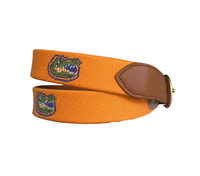 Cette ceinture en cuir brodée de style preppy présente une base orange et est ornée de la broderie emblématique du crocodile.