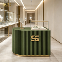 Comptoir de présentation de bijoux sur mesure, armoire incurvée cannelée verte avec cloche en verre trempé et bordure dorée pour boutique et aménagement de magasin de détail