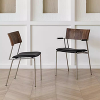 Chaise de salle à manger de style italien rétro de luxe épaissie, en acier inoxydable, avec accoudoirs en cuir véritable noir et assise rembourrée noire