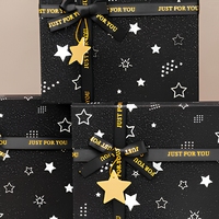 Boîte cadeau rigide à deux pièces noire avec logo personnalisé, impression étoile, paillettes, couvercle et base, avec ruban imprimé et pendentif étoile pour les fêtes