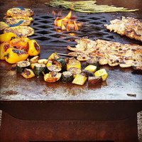Foyer rustique en acier corten avec grille de cuisson barbecue intégrée et écran pare-feu