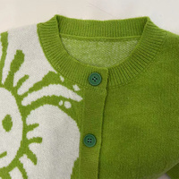 Cardigan en maille court à col ras du cou, motif jacquard asymétrique grande fleur souriante vert herbe, boutons de couleur assortie, vente directe usine