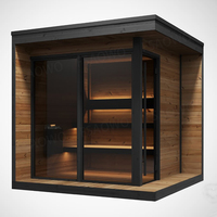 Sauna de exterior de gran tamaño con estructura de madera de hemlock, ventana de vidrio con marco negro, estufa Harvia, área de asientos en el alero y banco escalonado.