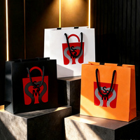 Sac cadeau en carton noir mat avec motif cœur rouge et logo brillant, robuste, idéal pour Noël et la Saint-Valentin