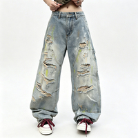 Jean long en denim style rétro américain, coupe courbée, effet vieilli et déchiré avec trous, peint avec des graffitis colorés
