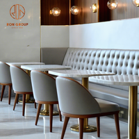Ensemble de mobilier de restaurant avec dessus de table en marbre et bases en métal doré, chaises en cuir gris à dossier haut et canapé banquette