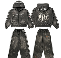 Ensemble de survêtement streetwear délavé avec sweat à capuche zippé et pantalon large, orné de patchs lettres gothiques Kornit DTG et rivets déchirés