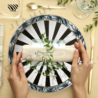 Ensemble d'assiettes en porcelaine avec feuilles tropicales, rayures radiales noires et blanches et motifs géométriques avec accents dorés