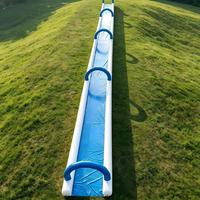 Toboggan aquatique gonflable géant à piste unique extra longue pour la location lors d'événements de carnaval estival en plein air sur les pentes herbeuses